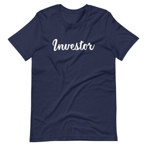 以下が含まれることがあります： 白い筆記体で「Investor」と書かれたネイビーブルーのTシャツです。