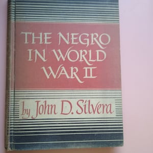 May include: A red and black book with the title "The Negro in World War II" by John D. Silv&eacute;ra.