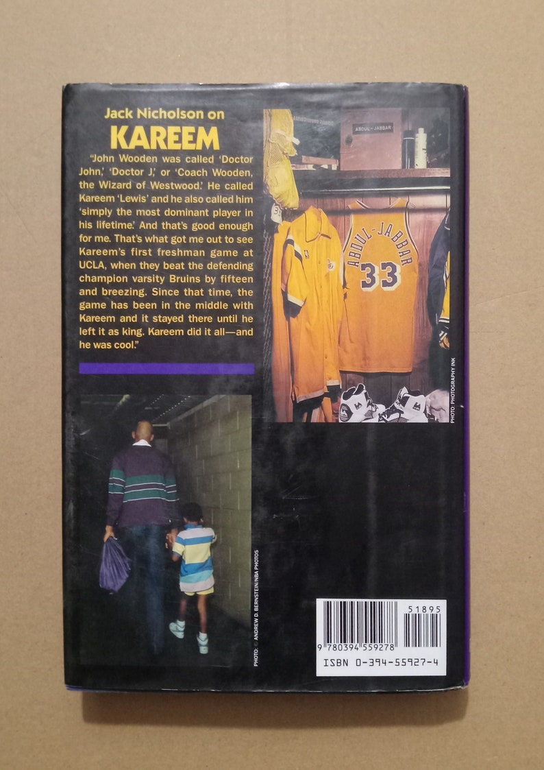 May include: A black and white photo of a man and a young boy walking down a hallway. The man is wearing a striped sweater and the boy is wearing a striped shirt. The text on the book cover reads "Jack Nicholson on Kareem".