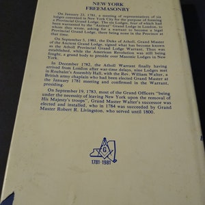 Puede incluir: Una p&aacute;gina de un libro sobre la historia de la masoner&iacute;a en Nueva York, con una ilustraci&oacute;n azul y blanca de un comp&aacute;s y una escuadra con la letra "G" en el centro. El texto de la p&aacute;gina describe la fundaci&oacute;n de la Gran Logia de Nueva York en 1781 y el desarrollo posterior de la organizaci&oacute;n. El texto tambi&eacute;n menciona al duque de Atholl, Gran Maestro de la Antigua Gran Logia, quien firm&oacute; la Orden de la Gran Logia Provincial de Atholl en 1781.