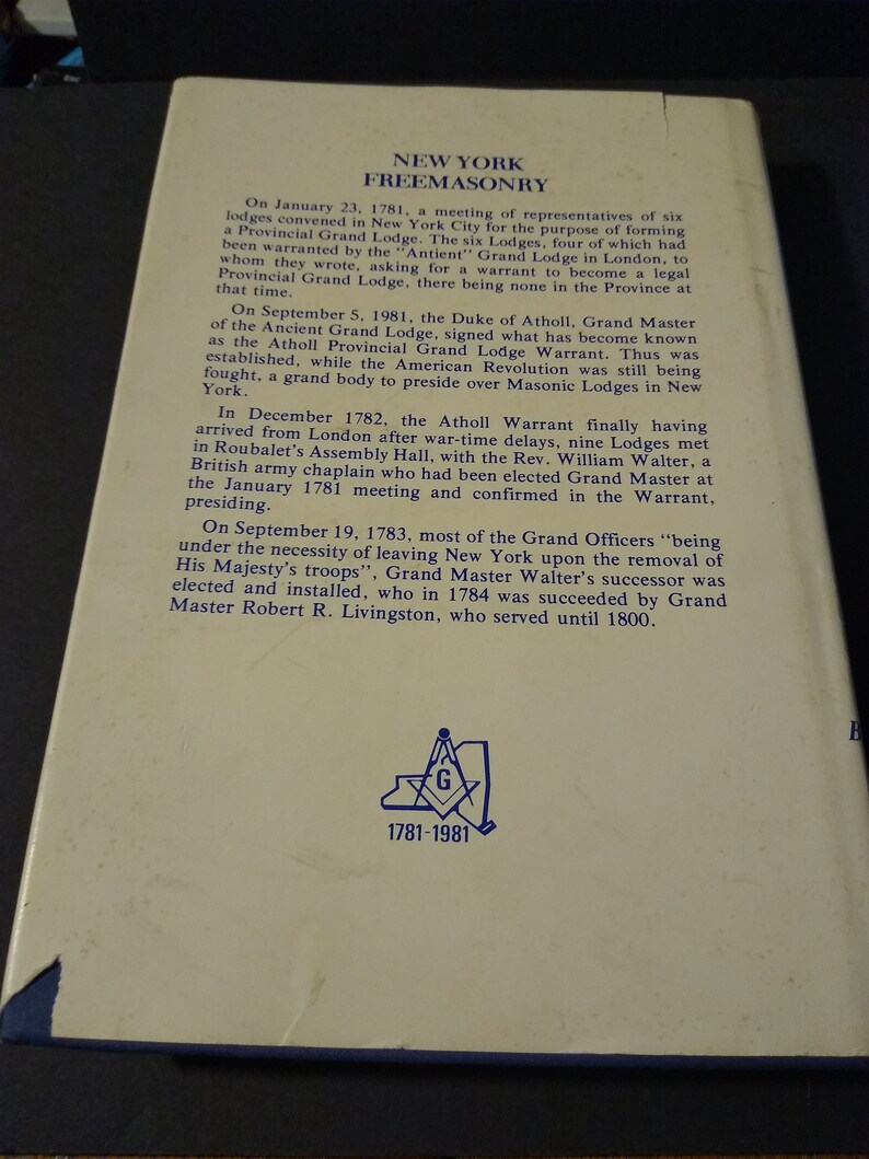 Puede incluir: Una p&aacute;gina de un libro sobre la historia de la masoner&iacute;a en Nueva York, con una ilustraci&oacute;n azul y blanca de un comp&aacute;s y una escuadra con la letra "G" en el centro. El texto de la p&aacute;gina describe la fundaci&oacute;n de la Gran Logia de Nueva York en 1781 y el desarrollo posterior de la organizaci&oacute;n. El texto tambi&eacute;n menciona al duque de Atholl, Gran Maestro de la Antigua Gran Logia, quien firm&oacute; la Orden de la Gran Logia Provincial de Atholl en 1781.
