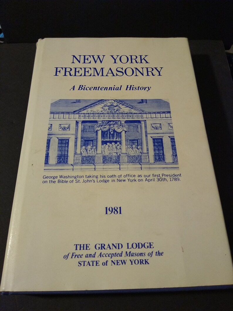 Puede incluir: Un libro blanco con texto azul que dice "New York Freemasonry: A Bicentennial History". La portada del libro presenta una ilustraci&oacute;n de un edificio con un grupo de personas frente a &eacute;l. El texto debajo de la ilustraci&oacute;n dice "George Washington tomando su juramento de cargo como nuestro primer presidente en la Biblia de la logia de San Juan en Nueva York el 30 de abril de 1789." El a&ntilde;o 1981 est&aacute; impreso debajo del texto. La parte inferior de la portada dice "The Grand Lodge of Free and Accepted Masons of the State of New York."