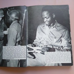May include: A black and white photograph of a military officer pinning a medal on a soldier's uniform. The soldier is smiling and holding a letter. The text in the image reads: "Sgt. The W. Andrus, Carbonale, Ill., has a double barreled reason for that smile. Mail came from home while he was being decorated with the Purple Heart for wounds suffered just when his camp was bombed. Sgt. Andrus had got to remove it to his lonely room to show it to the company commander when the mail came in. He got his lunch. "Never mind the medal, Sir," he said, grinning. "Here's just what I've been looking for - mail from home."