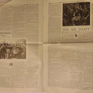 May include: A vintage newspaper page with two stories, "The Jitney Freshman" and "The Air Shaft". The Jitney Freshman story features a black and white illustration of a group of people gathered around a car. The Air Shaft story features a black and white illustration of miners working in a dark, underground mine.