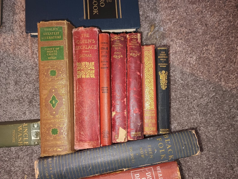 Puede incluir: Una colecci&oacute;n de libros antiguos de tapa dura con letras doradas y dise&ntilde;os decorativos. Los libros incluyen t&iacute;tulos como "El collar de la reina", "Los tres mosqueteros" y "El conde de Montecristo".