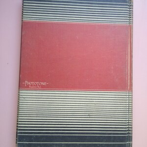 May include: A red book with black and white stripes on the cover. The book has the text "Phototone" and "Passaic, N.J." printed on the cover.