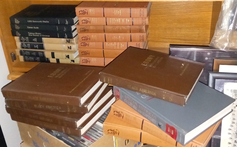 May include: A stack of brown hardcover books with the title "Ebony: The History of Black America" on the top book. There are other books in the stack with titles like "Black America" and "African American Culture and History".