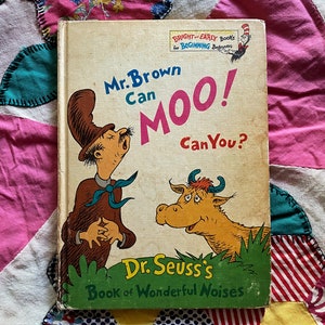 May include: A vintage children's book cover featuring a cartoon man in a hat and a cow. The book is titled "Mr. Brown Can Moo! Can You?" and is part of Dr. Seuss's Book of Wonderful Noises.