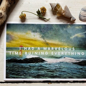 May include: A vintage postcard with a seascape image. The sky is a gradient of yellow, orange, and red. The ocean is a deep blue with whitecaps. The text on the postcard reads "I had a marvelous time ruining everything."