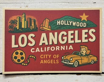 May include: A rectangular print with a red background featuring the text LOS ANGELES CALIFORNIA CITY OF ANGELS. It displays a city skyline, a green hill with a yellow star and the word HOLLYWOOD, a film reel, and a yellow convertible car.