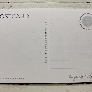 May include: A white rectangular postcard with black text and graphics. The top left reads POSTCARD, the center features a vertical line with MADE IN POWDER SPRINGS, GA, and the bottom right has the script text things are lovely.