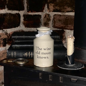 May include: White ceramic mug with a black handle, featuring the text "But First, Coffee" in black. The mug is displayed against a blurred backdrop, implying a comfortable environment.