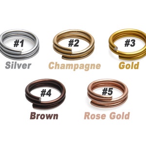 K&ouml;nnte beinhalten: F&uuml;nf Sprungringe in verschiedenen Metalloberfl&auml;chen: Silber, Champagner, Gold, Braun und Ros&eacute;gold. Jeder Ring ist mit einer Nummer von 1 bis 5 gekennzeichnet.