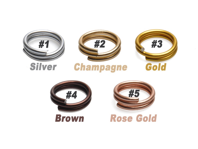 K&ouml;nnte beinhalten: F&uuml;nf Sprungringe in verschiedenen Metalloberfl&auml;chen: Silber, Champagner, Gold, Braun und Ros&eacute;gold. Jeder Ring ist mit einer Nummer von 1 bis 5 gekennzeichnet.
