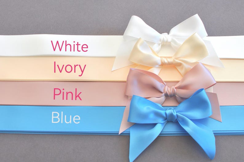 K&ouml;nnte beinhalten: Vier horizontale Satinb&auml;nder in Wei&szlig;, Elfenbein, Rosa und Blau, jeweils mit einer passenden Schleife auf der rechten Seite. Der Text White, Ivory, Pink und Blue ist in Rosa und Wei&szlig; auf der linken Seite des jeweiligen Bandes aufgedruckt.