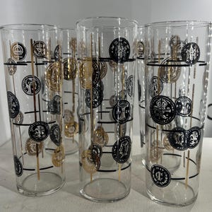 May include: Set of six clear glass highball glasses with a black and gold geometric design featuring coins. The design includes a repeating pattern of coins with black and gold accents.