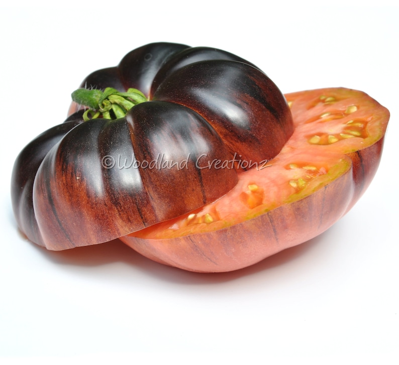 May include: A sliced heirloom tomato with a dark purple and reddish-brown exterior, revealing a vibrant red interior with visible seeds. The tomato is cut to showcase its texture and color variations. The image includes the text "Woodland Creationsz".