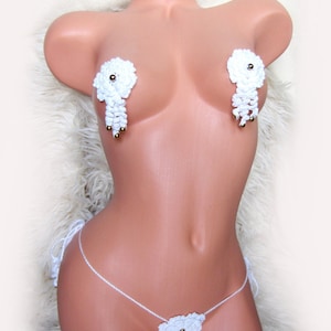 Puede incluir: Conjunto de lencería de crochet blanco con cuentas doradas. El conjunto incluye un par de pasties y un tanga.