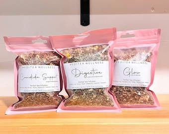 May include: Three pink pouches of herbal tea blends, labeled "Candida Support", "Digestive", and "Glow". Each pouch has a white label with the brand name "MEDITEA WELLNESS" and the tea type. The pouches are filled with dried herbs and spices.