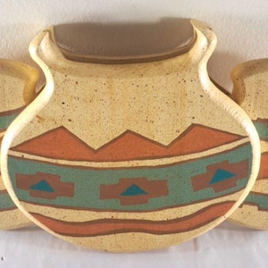 May include: Three ceramic vases with a Southwestern design. The vases are in a light tan color with brown, orange, and teal geometric patterns. The center vase has a brown top. The vases are arranged side by side.