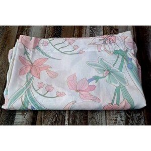 Könnte beinhalten: Ein weißer Stoff mit einem floralen Muster mit rosa, grünen und blauen Blumen. Der Stoff ist in der Hälfte gefaltet und hat eine glatte Textur.