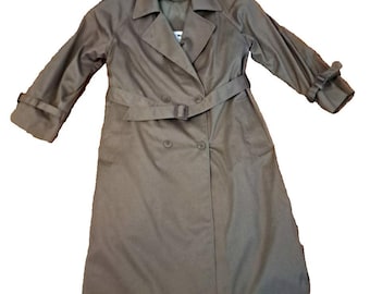 Puede incluir: Un abrigo tipo gabardina de color beige con diseño de doble botonadura, cinturón en la cintura y correas en las mangas. El abrigo tiene un cuello clásico y está hecho de una tela lisa. El abrigo está plano sobre un fondo blanco.