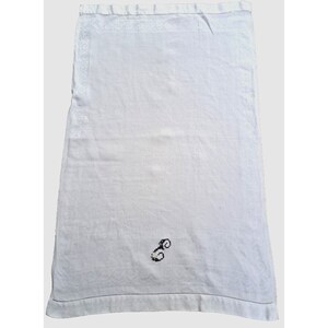 Puede incluir: Toalla de té de lino blanco con un diseño bordado en negro de una letra estilizada "S" en el centro.