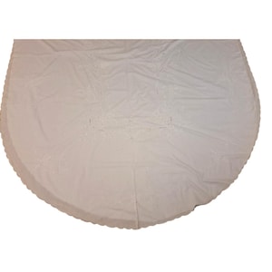 Op de afbeelding: Een grote, crèmekleurige, ronde tafelkleed met een geschulpte rand. De stof heeft delicate, geborduurde bloempatronen over het oppervlak. De stof lijkt een zachte, mogelijk linnen of katoenmix te zijn, geschikt voor formele diners.