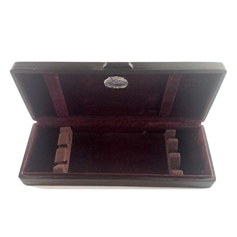 May include: An open wooden box with a burgundy velvet interior. The box has a small silver label with the text "Fine English Cutlery" on it. The box has compartments for holding cutlery.