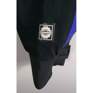 May include: Close-up of a black garment with a blue mesh accent. A square patch with the word "BOMBARDIER" and a gear design is visible. The garment has a ribbed cuff and a smooth, matte finish.