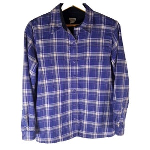 May include: A blue and white plaid flannel shirt with a button-up front and a single chest pocket. The shirt has a fleece lining.