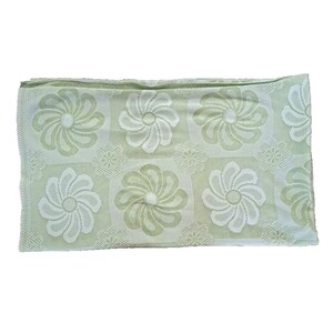 May include: A light green throw blanket with a white floral pattern. The blanket is made of a soft, textured fabric.