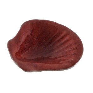 Puede incluir: Un plato de cerámica de forma de pétalo, de color rojo oscuro. El plato tiene un acabado liso y brillante y una forma ligeramente curvada.