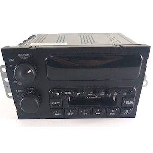 Peut inclure: Stéréo de voiture noire avec lecteur de cassette, tuner radio et boutons pour le volume, la balance, la fade, la recherche, les basses, les aigus et l'éjection. L'écran affiche "P SCAN".