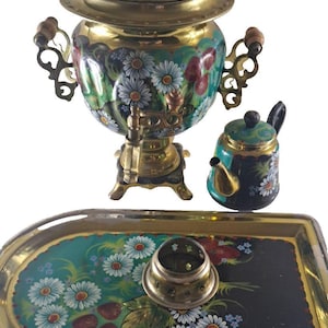 May include: A vintage samovar tea set with a matching tray. The samovar is gold and teal with a floral design. The set includes a small teapot and a tray with a floral pattern. The tray has a diameter of approximately 12 inches.