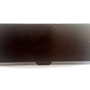 May include: A dark brown wooden box with a hinged lid and a small metal latch. The box has a worn, distressed finish.
