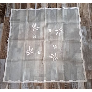 May include: White sheer tablecloth with a scalloped edge and embroidered floral designs.