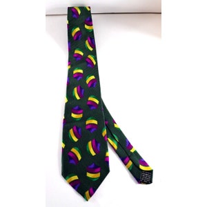 Puede incluir: Una corbata de seda verde con un patrón repetido de formas geométricas moradas, amarillas y verdes.