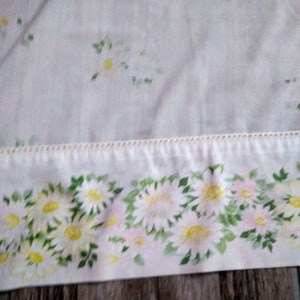 Puede incluir: Panel de cortina de voile blanco con estampado de margaritas blancas. El borde inferior de la cortina tiene un ribete blanco con una fila de pequeñas cuentas blancas.