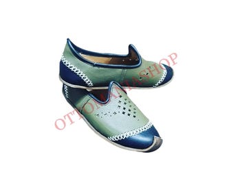 Può includere: Un paio di scarpe in pelle verde con finiture nere e cuciture bianche. Le scarpe hanno un design traforato e una punta arrotondata.