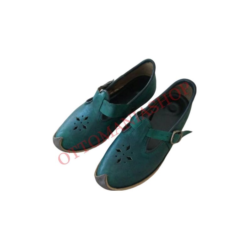 Puede incluir: Un par de zapatos de cuero verde con una correa de hebilla y dise&ntilde;os recortados. Los zapatos tienen una punta puntiaguda y un tac&oacute;n bajo.