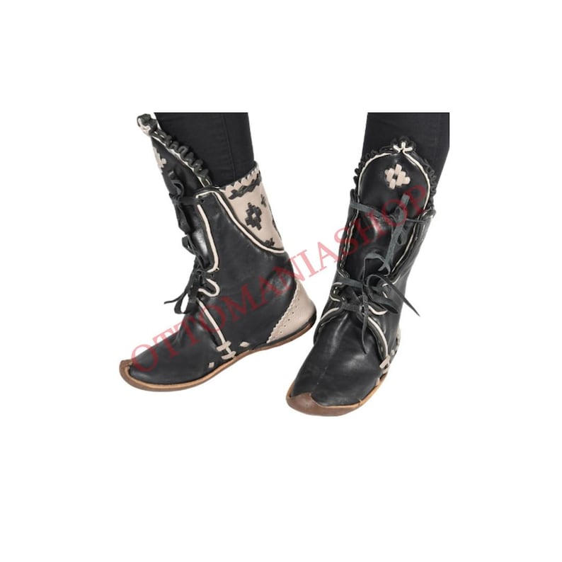May include: A pair of black leather boots with white embroidered details. The boots have laces and a pointed toe.