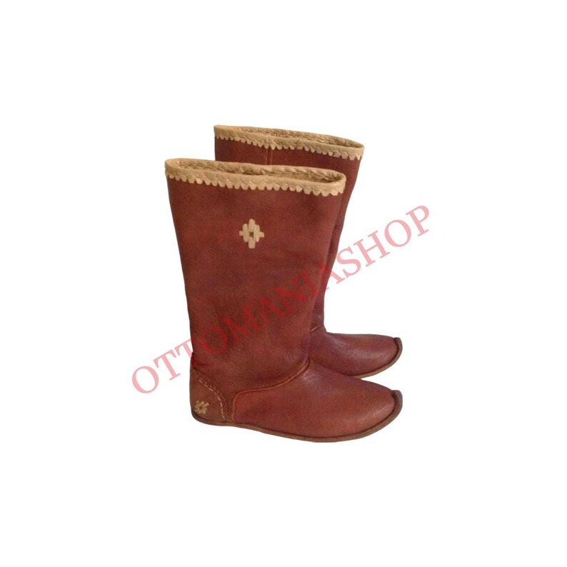K&ouml;nnte beinhalten: Ein Paar braune Lederstiefel mit einem beigefarbenen Besatz und einem rautenf&ouml;rmigen Design auf der Vorderseite. Die Stiefel sind hoch und haben eine spitze Zehenpartie.