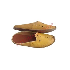 May include: A pair of tan leather slip-on shoes with a perforated design. The shoes have a rounded toe and a flat sole.