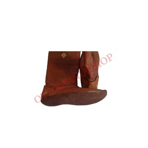K&ouml;nnte beinhalten: Ein Paar braune Lederstiefel mit Stickereien. Die Stiefel haben eine spitze Zehenpartie und einen niedrigen Absatz.