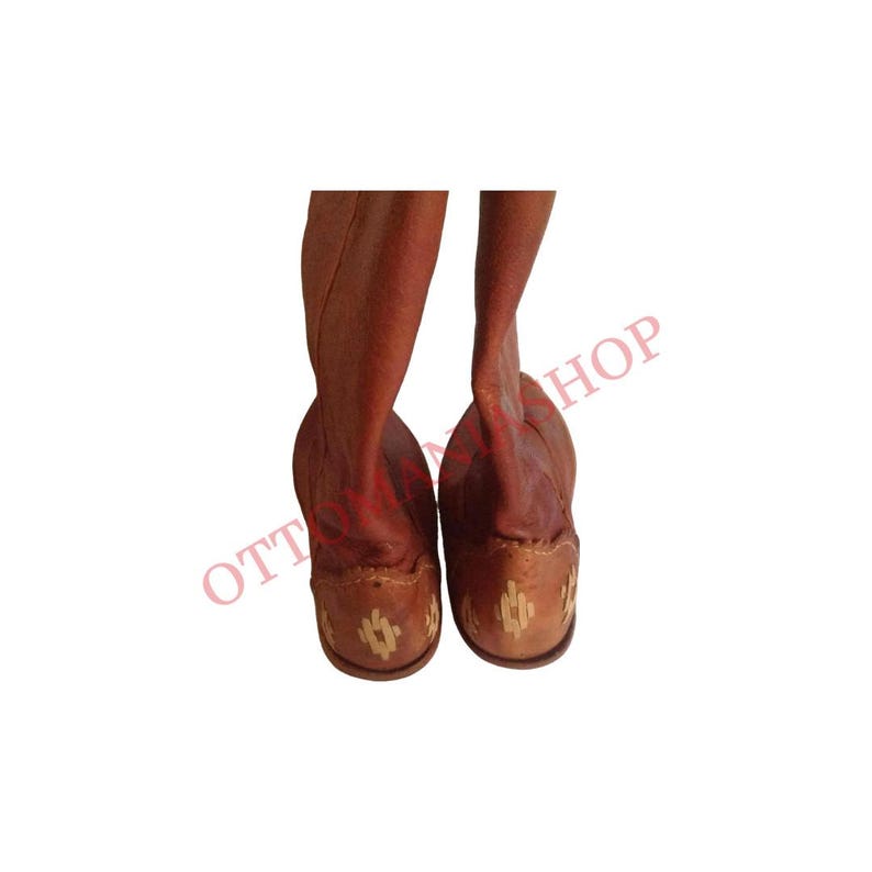 K&ouml;nnte beinhalten: Ein Paar braune Lederstiefel mit Stickereien auf der R&uuml;ckseite. Die Stiefel haben eine spitze Zehenpartie und einen niedrigen Absatz.