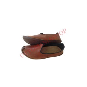 May include: A pair of brown leather slip-on shoes with a black trim around the edges. The shoes are made of a soft, supple leather and have a comfortable fit.