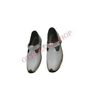 Puede incluir: Un par de zapatos de cuero blanco con una hebilla y una punta puntiaguda.