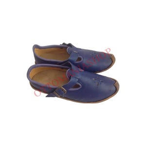 Puede incluir: Un par de zapatos de cuero azul con cierre de hebilla. Los zapatos tienen una punta redonda y un tac&oacute;n bajo.