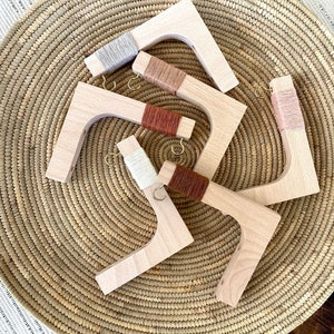 May include: Five wooden yarn holders with different colored yarn wrapped around them. The holders are arranged in a circle on a woven basket.